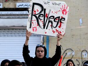 An Iranian regime supporter holds a placard during the final stage of funeral processions for slain top general Qasem Soleimani, in his hometown Kerman, January 7. (AFP)