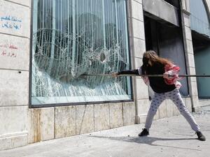 A Lebanese protester smashes the facade of a bank at Al-Nour square following the funeral of a fellow protester in Lebanon's northern port city of Tripoli, on April 28, 2020. Ibrahim CHALHOUB / AFP