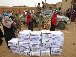 Sudanese people and security forces stand near boxes of aid at a region affected by flood in Tuti island, where the Blue and White Nile merge between the twin cities of the capital Khartoum and Omdurman, on September 3, 2020. ASHRAF SHAZLY / AFP