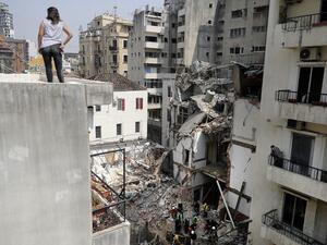 A woman looks on from a rooftop as rescue workers dig through the rubble of a badly damaged building in Lebanon's capital Beirut, in search of possible survivors from a mega-blast at the adjacent port one month ago, after scanners detected a pulse, on September 4, 2020. Lebanese rescuers scoured rubble for a possible survivor in Beirut after the detection of a pulse drew crowds hopeful of a miracle one month on from a devastating explosion. JOSEPH EID / AFP