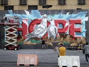 Onlookers watch as artists from the group REK paint a mural on a barrier erected in front of Le Grey hotel in Beirut's downtown district, depicting the city with the word "HOPE" inscribed on it, on September 4, 2020, one month after the August 4 massive blast at the nearby seaport that left scores of people dead or injured ravaged swaths of the Lebanese capital. JOSEPH EID / AFP