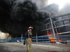 A firewoman walks past smoke billowing from a huge fire that raged in Beirut's port on September 10, 2020, sending a column of black smoke into the sky and sparking alarm among Lebanese still reeling from the devastating dockside blast last month.ANWAR AMRO / AFP