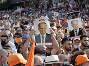 Supporters of Lebanese President Michel Aoun raise portraits of him as they gather near the presidential palace in Baabda, east of the capital Beirut on September 12, 2020, as others protest nearby to denounce a lack of progress in a probe by authorities into a monster blast that ravaged swathes of the capital 40 days ago. ANWAR AMRO / AFP