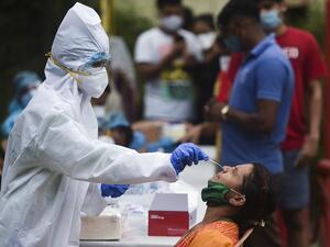 A medical staff wearing Personal Protective Equipment (PPE) takes a nasal swab sample from a resident for a Covid-19 Coronavirus test, in a residential area in Mumbai, on September 14, 2020. Punit PARANJPE / AFP