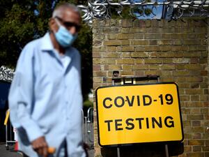 A man wearing a face covering due to the COVID-19 pandemic, waks past a sign outside a novel coronavirus walk-in testing centre in East Ham in east London, on September 17, 2020. British Prime Minister Boris Johnson said Thursday he could close pubs earlier to "stop the second hump" of coronavirus cases, comparing the country's trajectory of resurgent transmission to a camel's profile. But the prime minister has faced stinging criticism this week over the failure to achieve the "world-beating" testing and t