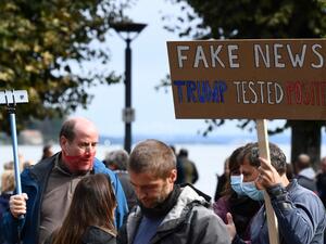 A demonstrator holds up a placard reading 'Fake news - (US President Donald) Trump tested positive' to protest against masks and virus restrictions during the ongoing Covid-19 pandemic (novel coronavirus) in Konstanz, southern Germany, on October 3, 2020. SEBASTIEN BOZON / AFP