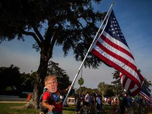 A man wearing a mask of US President Donald Trump holds a US flag during a pro-Trump rally in Beverly Hills, California on October 3, 2020. Apu GOMES / AFP