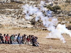 Palestinian protesters pray amidst tear gas smoke fired by Israeli security forces to disperse a demonstration against the expansion of settlements, near the village of Beit Dajan, east of Nablus, on October 9, 2020. JAAFAR ASHTIYEH / AFP