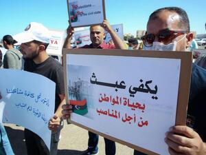 Libyans lift placards making demands on participants in talks between the country’s two rival administrations, in front of the headquarters of the UN Mission, in the city of Janzour, west of the Libyan capital, October 14. (AFP)