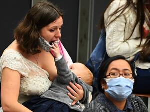 A woman breastfeeds her child, that jokes with her face mask, during the Pope Francis' weekly general audience at Paul VI hall on October 21, 2020, at the Vatican. Vincenzo PINTO / AFP