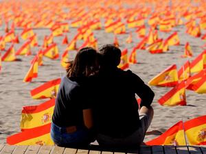 In this file photo taken on October 4, 2020 a couple sit next to thousands of Spanish flags, representing the Spanish victims of COVID-19, on Patacona beach in Valencia. Spain surpassed one million virus cases on October 21, 2020 according to health ministry figures. Jose Jordan / AFP