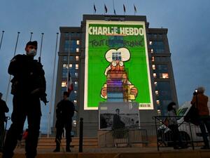 Police officers stand guard as cartoons of French satirical weekly newspaper Charlie Hebdo are projected onto the facade of the Hotel de Region in Montpellier, on October 21, 2020, during a national homage to French teacher Samuel Paty who was beheaded for showing cartoons of the Prophet Mohamed in his civics class. (AFP)