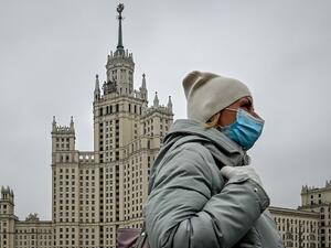 A woman wearing a face mask to protect against the coronavirus disease walks along a bridge near a Stalin-era skyscraper in central Moscow on October 22, 2020. Yuri KADOBNOV / AFP
