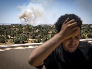 In this file photo taken on April 29, 2019, a fighter loyal to the internationally-recognised Government of National Accord (GNA) stands on a rooftop as smoke rises in the distance during clashes with forces loyal to strongman Khalifa Haftar, in Espiaa. (AFP)