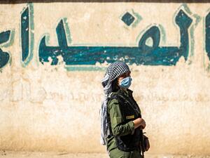 A Syrian Kurdish fighter stands guard during a rally in support of the Syrian Democratic Forces (SDF) and the People's Protection Forces and to denounce the recent attacks by Turkish forces on northeastern Syria, in the northeastern Syrian city of Qamishli, on October 24, 2020. Delil SOULEIMAN / AFP