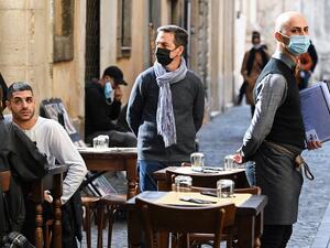 People sit at a restaurant's terrace in downtown Rome as a waiter looks on, on October 25, 2020, as the country faces a second wave of infections to the Covid-19 (the novel coronavirus).  (AFP/File)