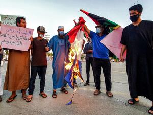 Demonstrators set fire to a French national flag during a rally protesting against the comments of French President Emmanuel Macron over Prophet Mohammed cartoons, at the Martyrs' Square of Libya's capital Tripoli on October 25, 2020. Mahmud TURKIA / AFP