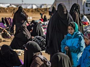 Women and children sit outdoors on the ground at the Kurdish-run al-Hol camp for the displaced in Hasakah province in northeastern Syria on Jan. 14, 2020, where families of Islamic State fighters are held. Photo by Photo by DELIL SOULEIMAN/AFP via Getty Images.