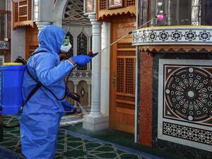 A Worker dressed in personal protective equipment sterilizes the mihrab of a mosque in Jordan's capital Amman on June 3, 2020, ahead of its reopening. Photo File by KHALIL MAZRAAWI/AFP via Getty Images. 
