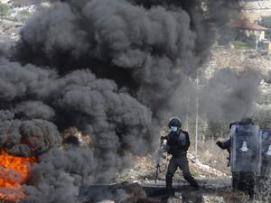Israeli security forces take position behind burning tyres during clashes with Palestinian demonstrators at a weekly demonstration in the West Bank village of Kfar Qaddum on October 16, 2020. JAAFAR ASHTIYEH / AFP