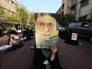 An Iranian protester holds a portrait of the supreme leader of the Islamic republic of Iran, Ayatollah Ali Khamenei, during a protest against comments made by the French president to defend secular values and cartoons mocking the prophet, outside the French embassy in Tehran on October 28, 2020. (AFP)