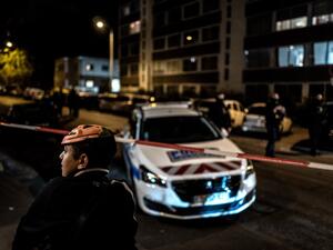 A boy wearing an Halloween mask looks away in foreground as French soldiers and Municipal Police officers stand behind a cordon-off area near the Orthodox Church where an attacker armed with a sawn-off shotgun wounded an Orthodox priest in a shooting before fleeing, on October 31, 2020 in Lyon, said a police source. JEFF PACHOUD / AFP