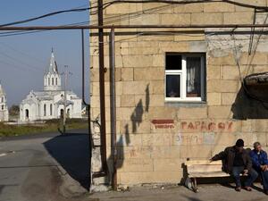 Men sit on a bench in front of residential building not far from the damaged Ghazanchetsots (Holy Saviour) Cathedral in the historic city of Shusha, some 15 kilometers from the disputed Nagorno-Karabakh province's capital Stepanakert, that was hit by a bomb during the fighting between Armenia and Azerbaijan over the breakaway region, on November 1, 2020. Karen MINASYAN / AFP