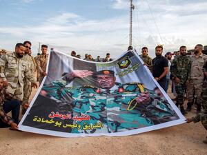 Members of the the "Saiqa" (Special Forces) of the self-proclaimed Libyan National Army (LNA), loyal to eastern strongman Khalifa Haftar, pose for a group picture with a banner depicting the unit's late commander General Wanis Bukhamada, who died a week prior, during a commemoration event in the eastern city of Benghazi on November 6, 2020. Abdullah DOMA / AFP