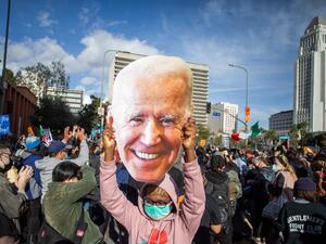 A woman holds a Joe Biden mask as people march in Los Angeles celebrating after Joe Biden was declared the winner of the 2020 presidential election on November 7, 2020. Democrat Joe Biden has won the White House, US media said November 7, defeating Donald Trump and ending a presidency that convulsed American politics, shocked the world and left the United States more divided than at any time in decades. Apu GOMES / AFP