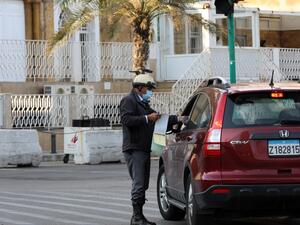 A policeman books a driver near the seaside corniche in the Lebanese capital Beirut, a day after the country went into lockdown, in a bid to stem the spread of the novel coronavirus, on November 14, 2020. AFP
