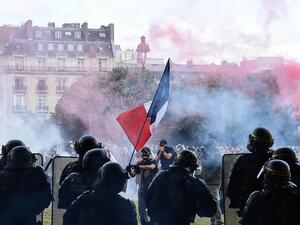 Protesters with a French flag face police during clashes on the Invalides esplanade at a demonstration in Paris. 16 June 2020 . (ALAIN JOCARD/AFP or licensors)