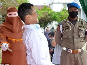 A child rapist cries out and grimaces as he is publicly flogged by a member of the sharia police after he was found guilty of raping and molesting a minor in Indonesia's ultra-conservative Aceh province. AFP