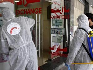 Volunteers with Lebanon's Disaster Management Unit disinfect a currency exchange in the southern city of Saida on March 12, 2020 to prevent the spread of coronavirus. AFP