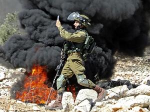 A member of the Israeli security forces takes a photograph with his telephone during clashes with Palestinian protesters after a weekly demonstration in the West Bank village of Kfar Qaddum, on October 23, 2020. JAAFAR ASHTIYEH / AFP