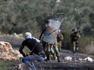A Palestinian demonstrator uses a slingshot to hurl stones toward Israeli security forces during clashes with them following a weekly demonstration in the occupied West Bank village of Kfar Qaddum, on November 13, 2020. JAAFAR ASHTIYEH / AFP
