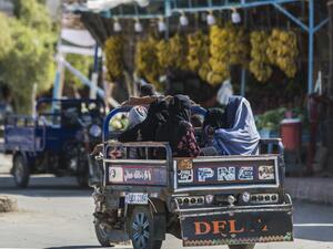Women clad in veils sit in the back of a tricycle cart moving along a road in Egypt's western desert oasis of Siwa, some 600 kilometres from the capital, on November 6, 2020. In Egypt's western desert oasis of Siwa, the "Siwi" local Berber dialect remains clinging to life in the face of the dominance of Arabic which is used by only a few adults as their main language. AFP