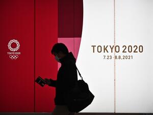 A man walks along a corridor past an official Tokyo 2020 Summer Olympics advertisement board in the Shinjuku district of Tokyo on November 30, 2020. Philip FONG / AFP