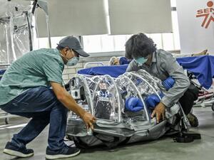A student and a professor demonstrate how a depressurized cabin designed to transport COVID-19 patients works in Medellin, Colombia, on December 16, 2020. The cabin was designed and developed by an alliance led by the Ministry of Science, the National University and the SENA technical college. JOAQUIN SARMIENTO / AFP