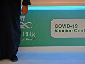 A man stands next to a sign at a location where the the Pfizer-BioNTech COVID-19 coronavirus vaccine (Tozinameran) is being administered by Saudi health authorities in the capital Riyadh on December 17, 2020. FAYEZ NURELDINE / AFP