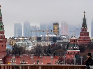 A woman walks in front of the Kremlin and skyscrapers of the Moscow International Business Centre (Moskva City) in Moscow on December 17, 2020. Yuri KADOBNOV / AFP