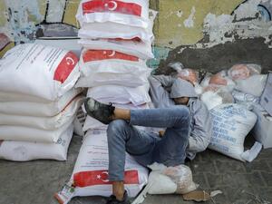 A worker rests amid food rations outside an aid distribution center run by the United Nations Relief and Works Agency (UNRWA) at the al-Shati camp for Palestinian refugees in Gaza City on December 12, 2020. Mohammed ABED / AFP