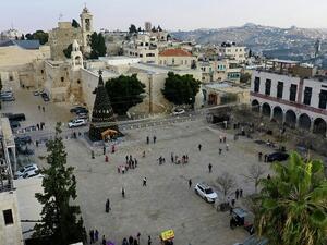 Locals visiting the Christmas tree in front of the Church of the Nativity, in the West Bank city of Bethlehem, December 22, 2020. (HAZEM BADER / AFP)