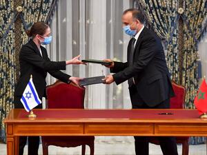 Chief economist at Israel's Ministry of Finance Shira Greenberg (L) and Morocco's Director General Of the Customs and Indirect Tax Administration at the Ministry of Economy and Finance Nabil Lakhdar exchange a signed agreement at the Royal Palace in the Moroccan capital Rabat on December 22, 2020, on the first Israel-Morocco direct commercial flight, marking the latest US-brokered diplomatic normalisation deal between the Jewish state and an Arab country.  FADEL SENNA / AFP