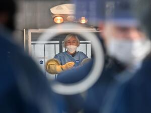 A medical staff member (C) wearing protective gear in a booth prepares to give tests for the COVID-19 coronavirus at a temporary testing station outside the City Hall in Seoul on December 23, 2020, as South Korea banned gatherings of more than four people in the capital and surrounding areas amid a surge in infection cases. Jung Yeon-je / AFP