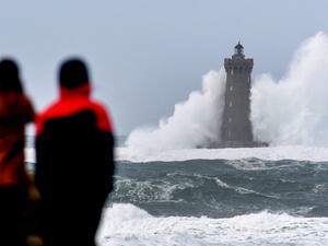 People watch high waves and strong winds hitting The Four Lighthouse (Lighthouse of the Four d'Argenton) at Porspoder, western France on December 27, 2020, as Storm Bella strikes the coast of Britanny. Fred TANNEAU / AFP