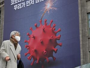 An elderly woman walks past a poster depicting the coronavirus as a bomb to warn against the Covid-19 coronavirus at the City Hall in Seoul on December 28, 2020. Jung Yeon-je / AFP