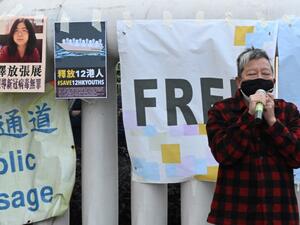 Democracy activist Lee Cheuk-Yan speaks outside China's Liaison Office in Hong Kong on December 28, 2020, during a protest calling on China to free a group of Hong Kong democracy activists facing trial in China, after they attempted to flee the territory by speedboat to Taiwan last August, as well as Chinese citizen journalist Zhang Zhan (top L poster) who was jailed for four years for her livestream reporting from Wuhan as the Covid-19 outbreak unfurled.  Peter PARKS / AFP