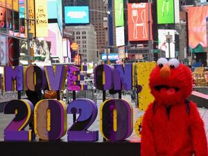 A person dressed as Elmo walks past a sign reading 'Move On 2020!' at Times Square on December 28, 2020 in New York City. Angela Weiss / AFP