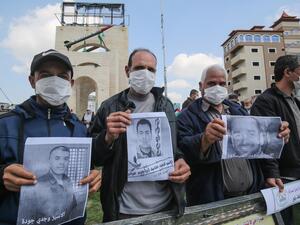 Palestinians, wearing protective masks amid fears of the spread of the novel coronavirus, take part in a protest in solidarity with Palestinian prisoners in Israeli jails, 16 March (AFP)