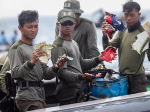 غطاسون من البحرية الاندونيسية يعرضون قطعا من حطام طائرة البوينغ